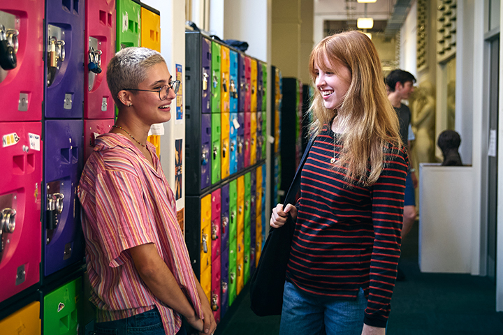 Two young female students chat to each other while standing by a wall of colourful lockers at Bradfield campus.