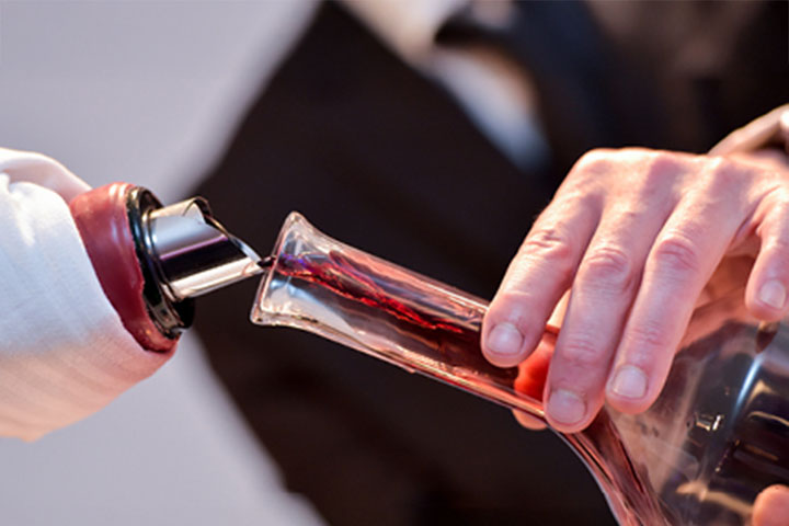 Close up sommelier image showing red wine being poured into a decanter.