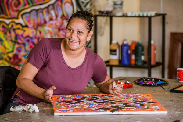 Person painting a colourful artwork at a table.