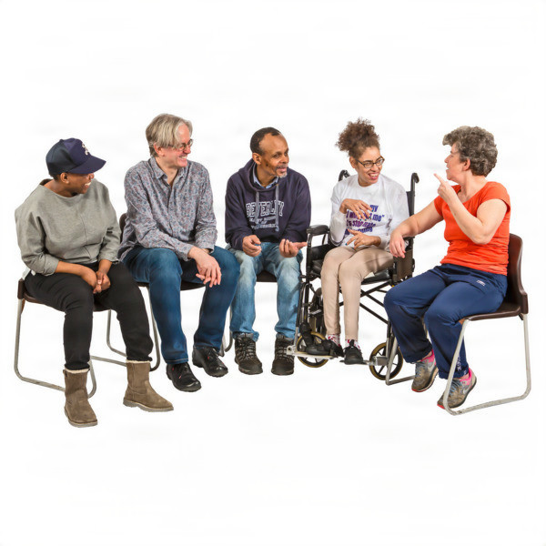A diverse group of five people sitting and talking together, with one person in a wheelchair.