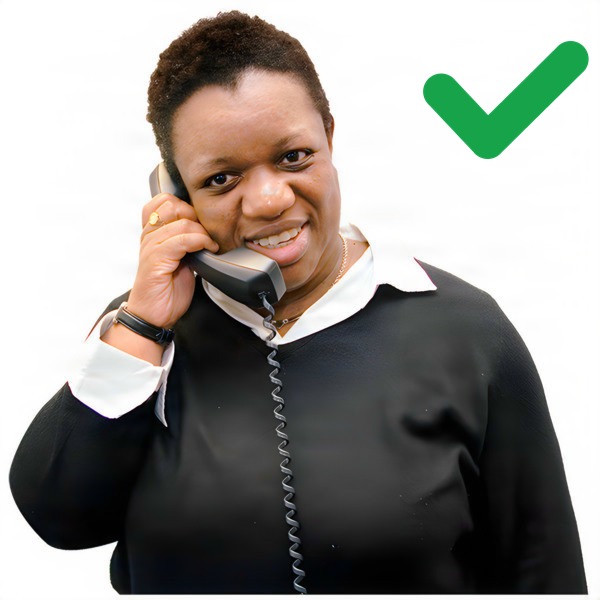 Person holding a corded telephone and smiling with a green tick.