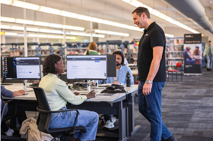 A person talking to students in a library.