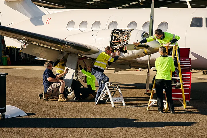 Aviation mechanic teacher guiding students as they work on a plane engine