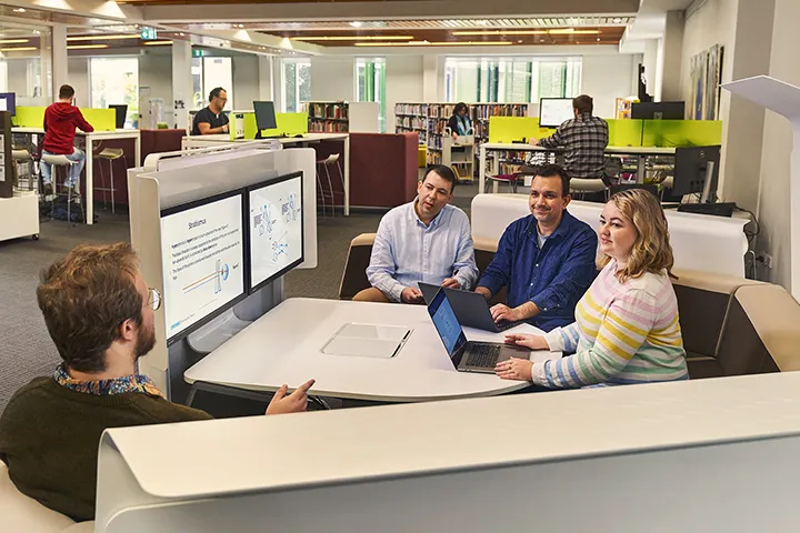 Collaborative discussion among adult students in a library pod setting.