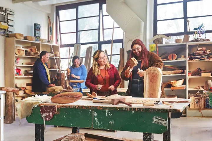 A female Aboriginal teacher guides a young student working on a sculpture project.