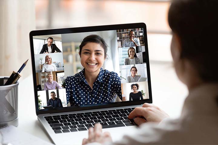 A person working on her laptop in their home office, participating in a Zoom call with team members.