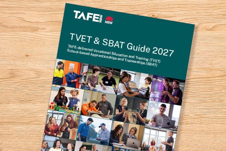 TAFE NSW TVET and SBAT Guide 2027 booklet displayed on a wooden surface, featuring a green cover with the title “TVET & SBAT Guide 2027” and a collage of students participating in hands‑on vocational training activities such as construction, childcare, hospitality, and technology.